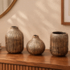 Antique ceramic vase set of 3 featuring ribbed bronze finish displayed on a wooden surface