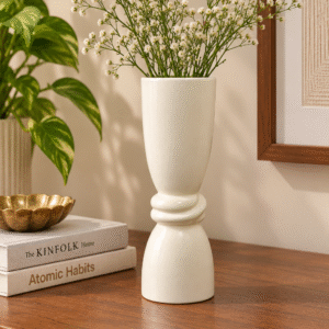 Ivory ceramic decorative vase styled with white flowers on a wooden console table in a modern living room